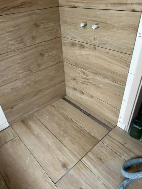 Dusche mit Holzoptik-Fliesen und Entwässerungsrinne